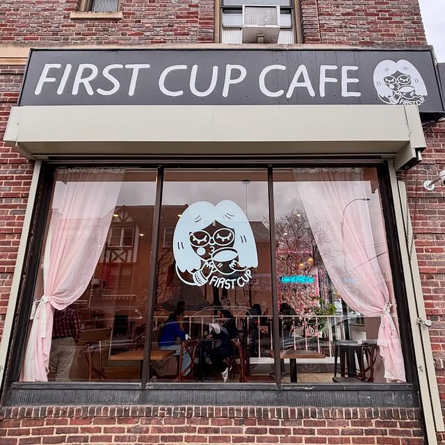 The First Cup Cafe storefront on 36th Ave — black awning, pink curtains, mascot window decal